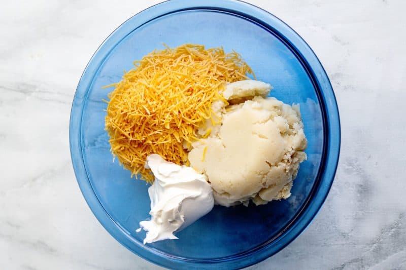 Place cheese, sour cream, and mashed potato in mixing bowl.