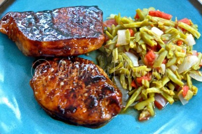 Green beans and tomatoes on plate with pork chops.