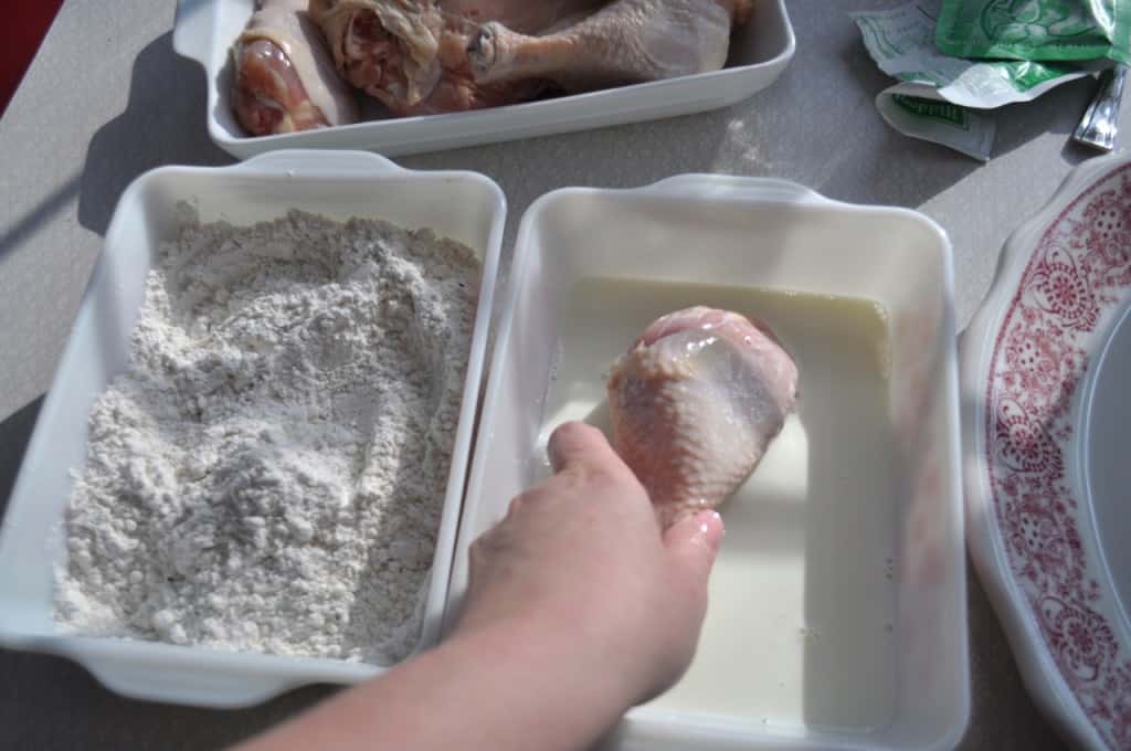 Fuss Free Fried Chicken - This is a way to actually fry chicken, in oil, in your oven A hand placing a chicken drumstick in a shallow dish of milk.