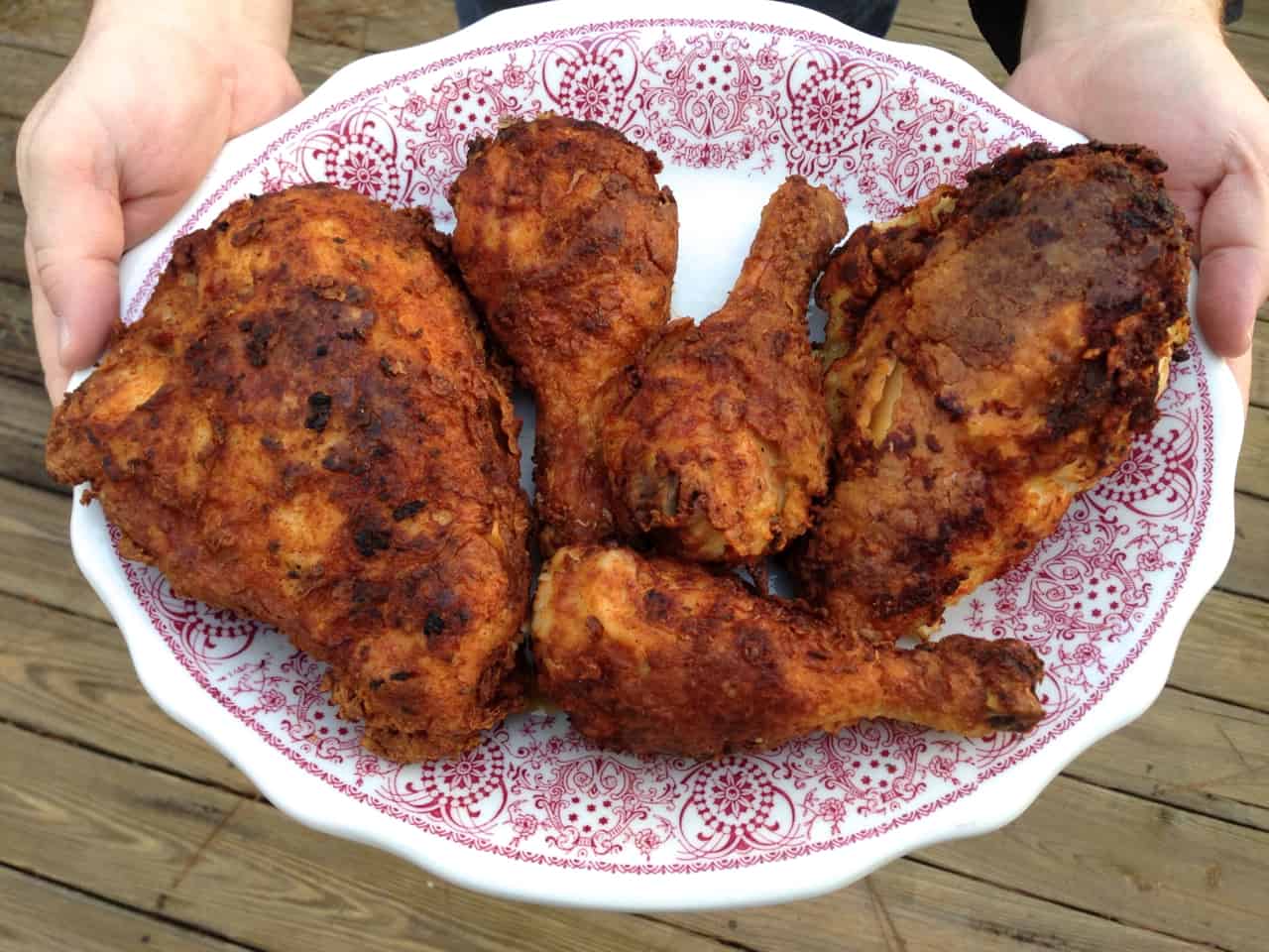 Fuss Free Fried Chicken - This is a way to actually fry chicken, in oil, in your oven A hand holding a decorative plate of Southern fried chicken.