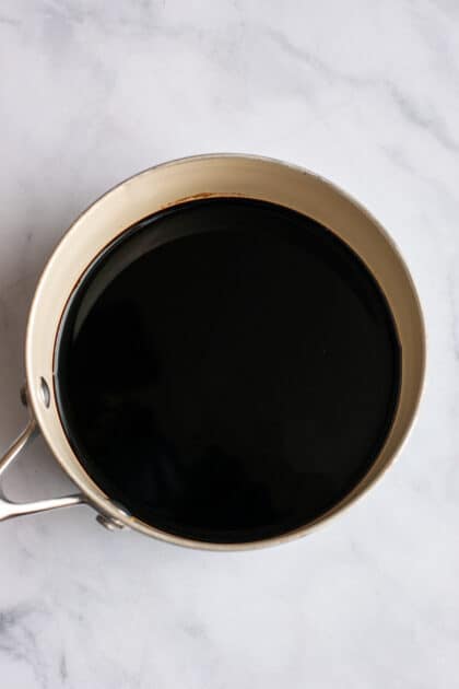 Balsamic vinegar in a pot over a white marble surface.