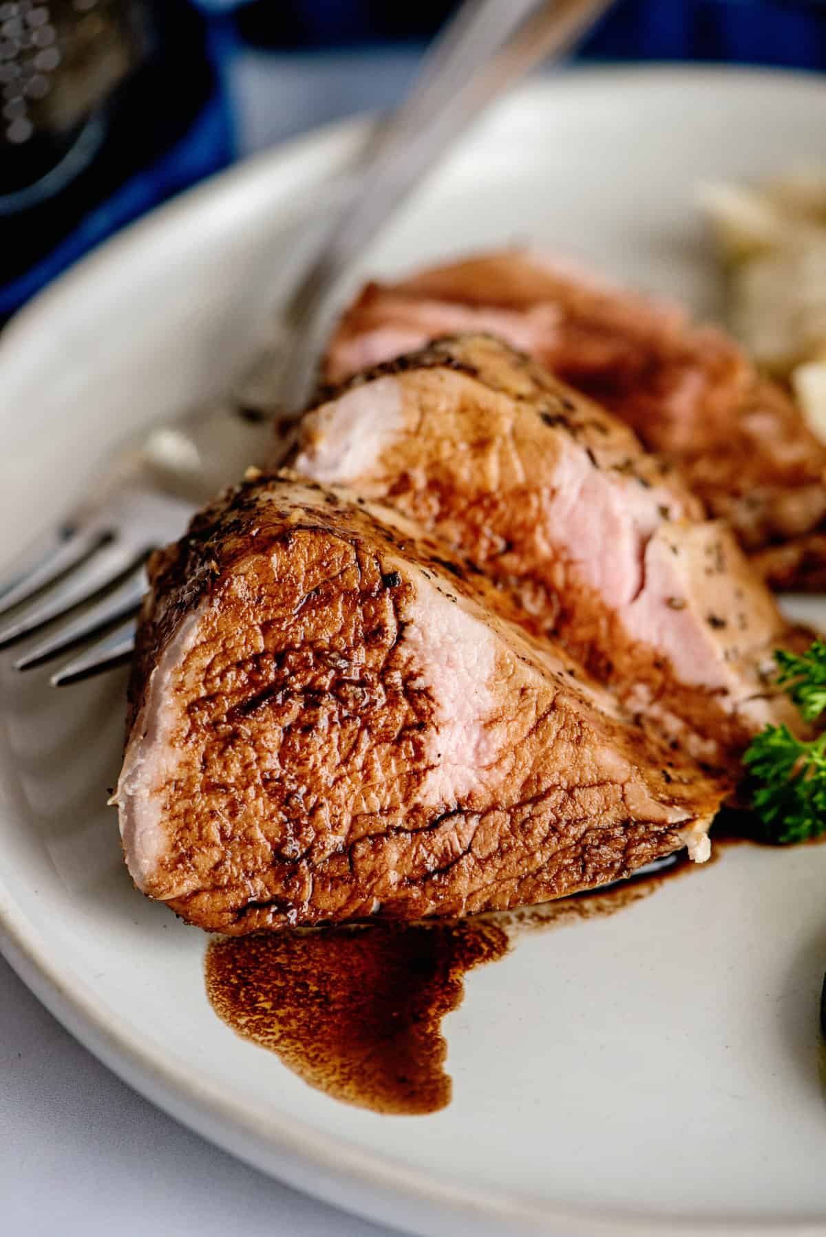 Close-up of sliced pork tenderloin with balsamic reduction.
