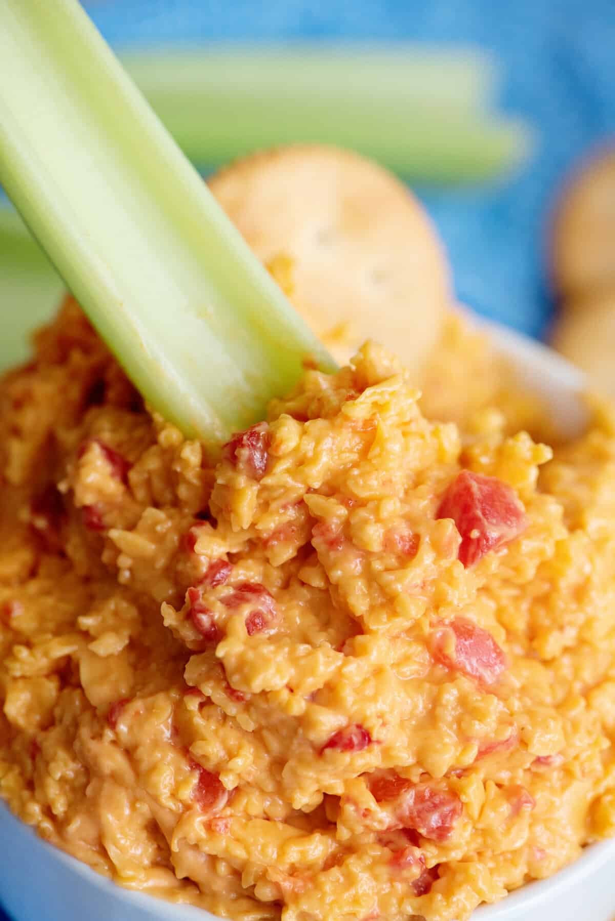 Celery stick dipping into spicy pimento cheese.