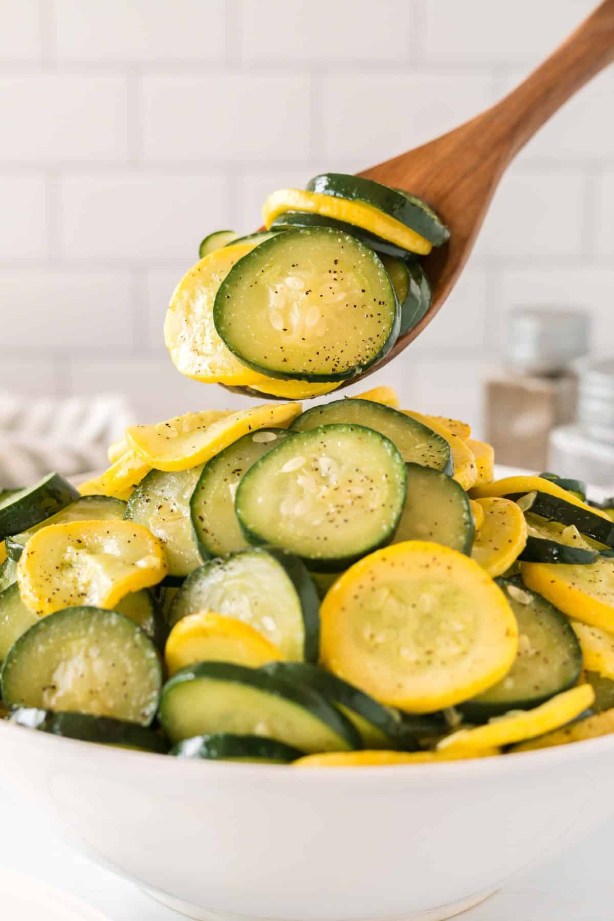 Spoon lifting zucchini and squash out of a bowl