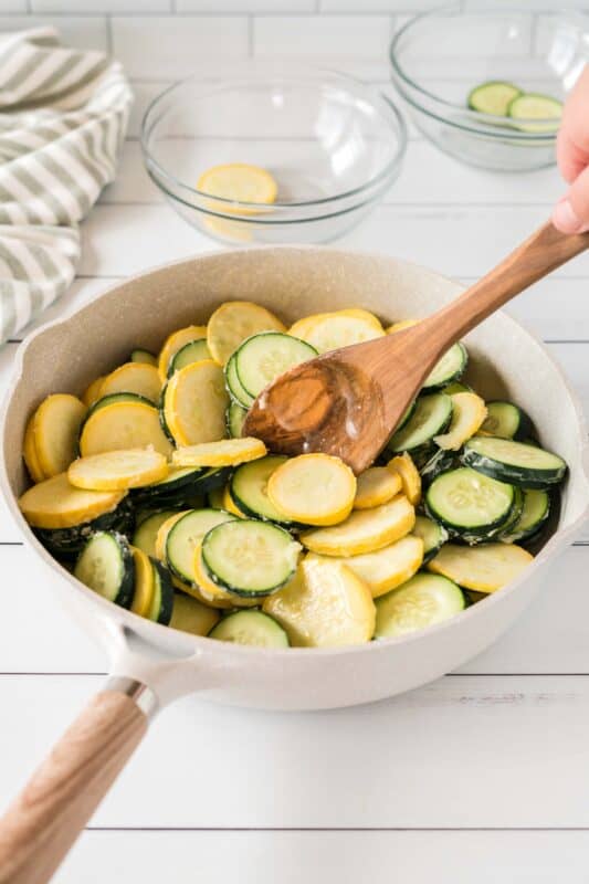 Adding zucchini and squash to a skillet to sautee