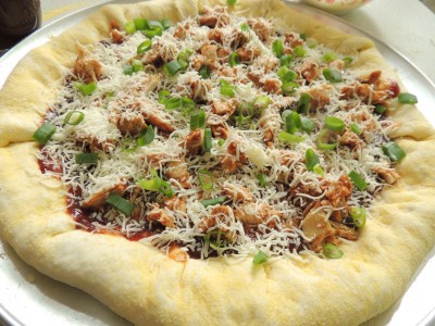 Top pizza with sliced green onions and more cheese.