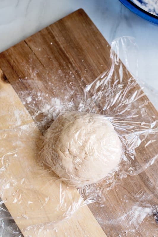 Loosely cover pizza dough with plastic wrap