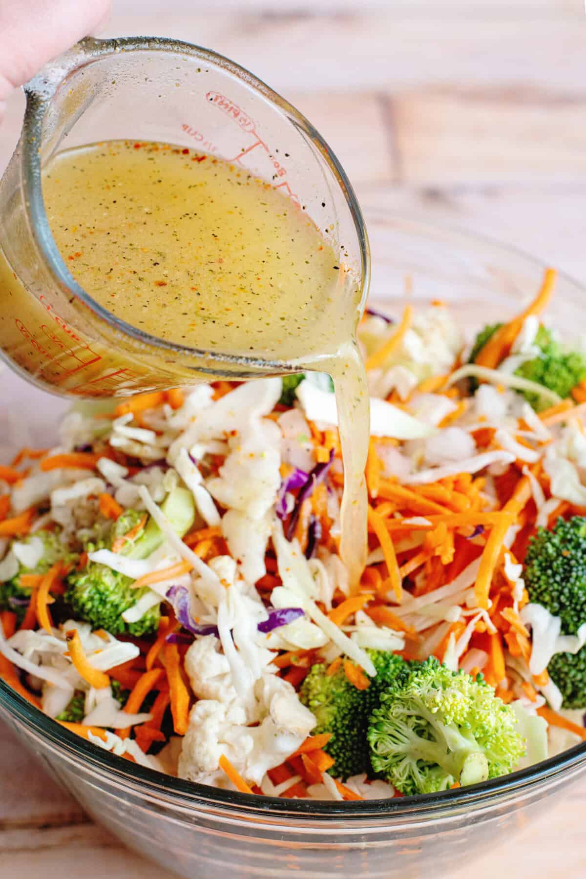 Pouring salad dressing into refrigerator salad.
