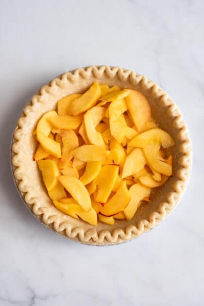 Place sliced peaches into unbaked pie crust.