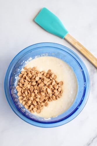 Peanut butter chips added to wet ingredients in mixing bowl.