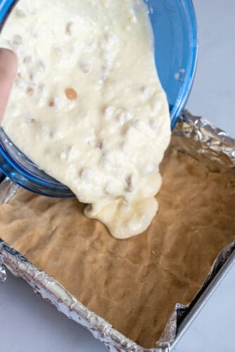 Pouring cream cheese mixture on top of cookie dough base.