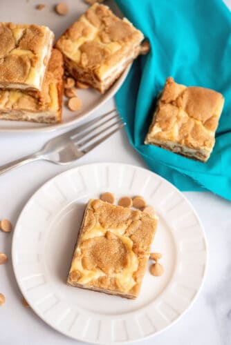 Peanut butter cheesecake cookie bars on a plate, with more in background.