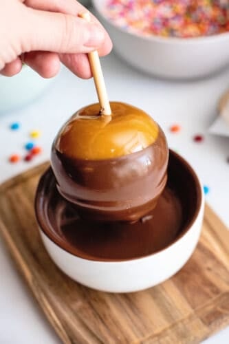 Dipping caramel apple in chocolate.