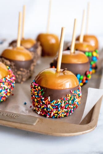 Assortment of chocolate caramel apples covered in sprinkles and M&Ms.