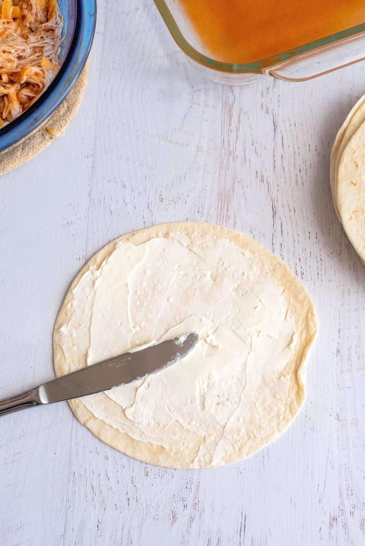  Spread cream cheese on a flour tortilla.  