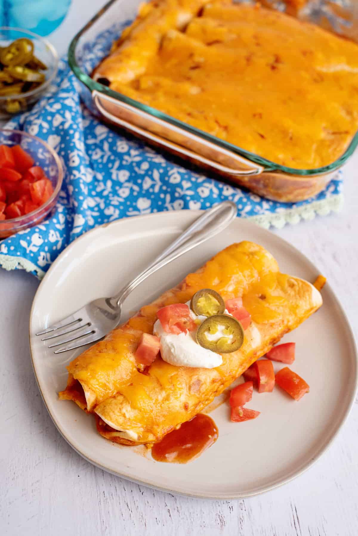 Plate of chicken enchiladas with toppings.