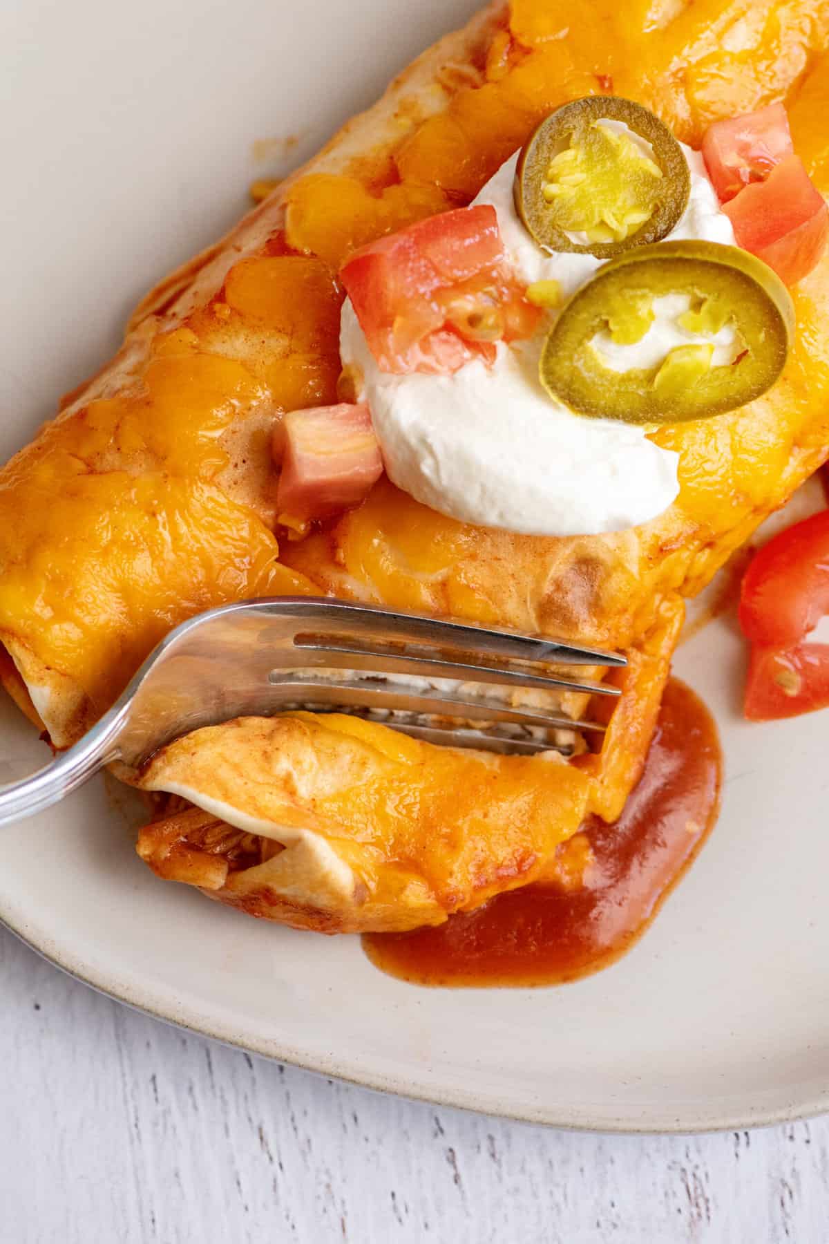 Fork breaking into cream cheese chicken enchilada.