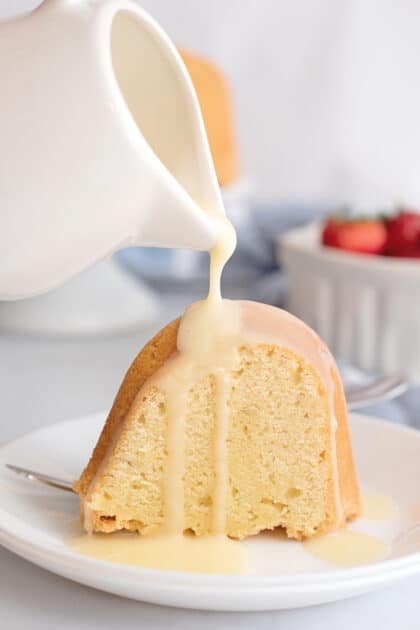 Pouring custard sauce over slice of pound cake.