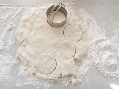 Cutting dough with a biscuit cutter.