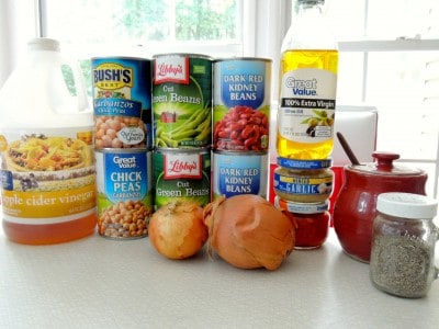 Ingredients for our 3 Bean Salad recipe, including apple cider vinegar, several cans of beans and onions.
