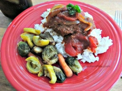 Serve crockpot Swiss Steak with vegetables and rice.