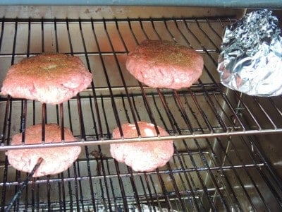 burger patties and foil wrapped ingredients placed in
smoker