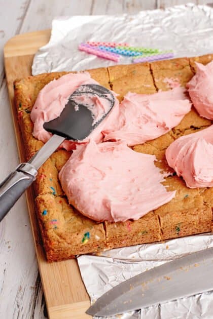 Spread buttercream frosting over birthday cake cookies