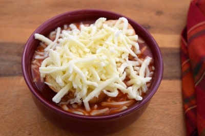 Top bowls of pizza soup with bread and cheese and broil.