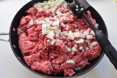 Raw beef and onions cooking in a grill.