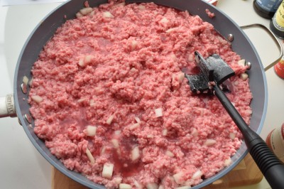  Ground beef and onions cooking in pan.