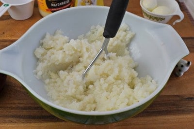 Mash potatoes with a potato masher.