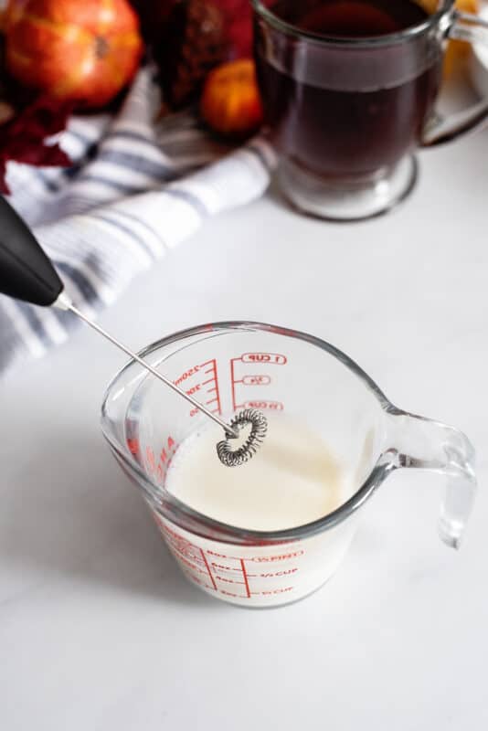 Frothing milk with handheld frother.