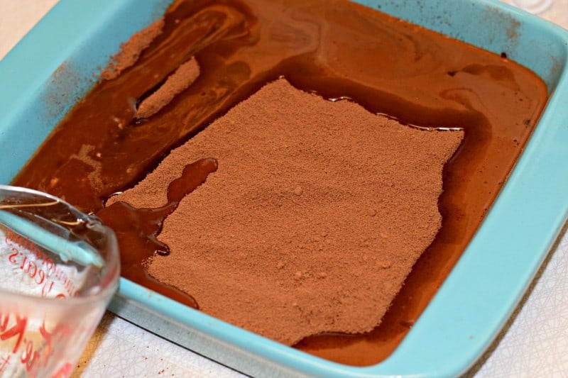 Slowly pour hot water over chocolate cobbler batter in baking dish.