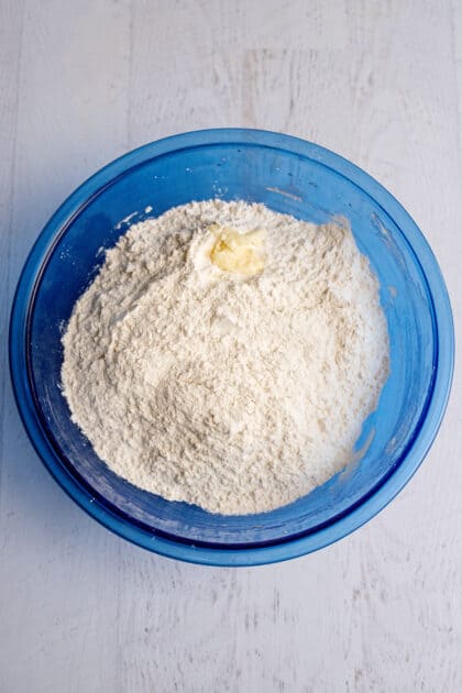 Flour and butter in a glass blue mixing bowl.