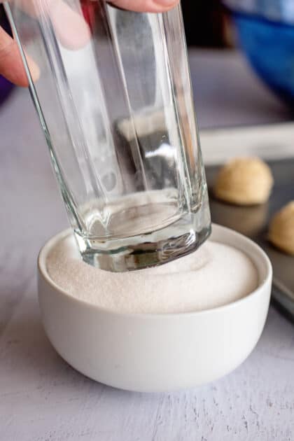 Dipping a glass cup in a bowl of granulated sugar.