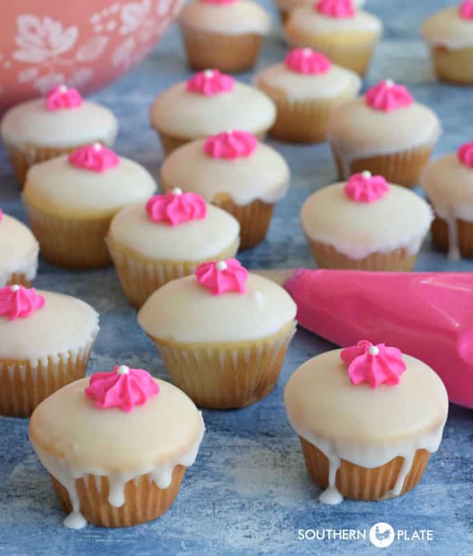 Pretty cake mix mini cupcakes with a vanilla glaze and pink flower on top.