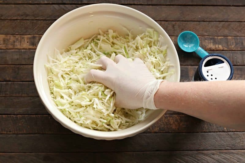 Squeeze cabbage in bowl with hands.