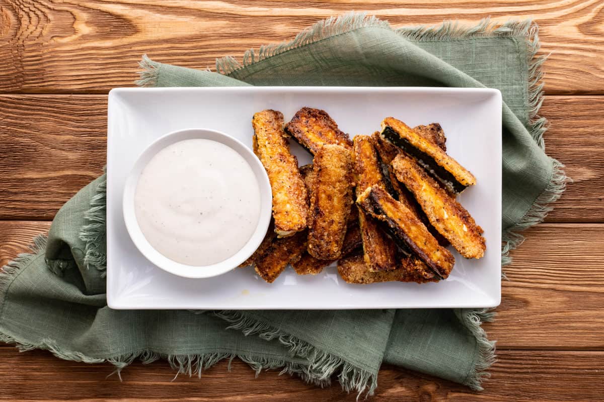 Plate of baked zucchini fries with dipping sauce.