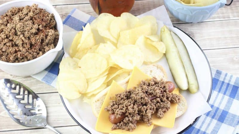 Hot Dog Chili dog on plate with chips and pickles 