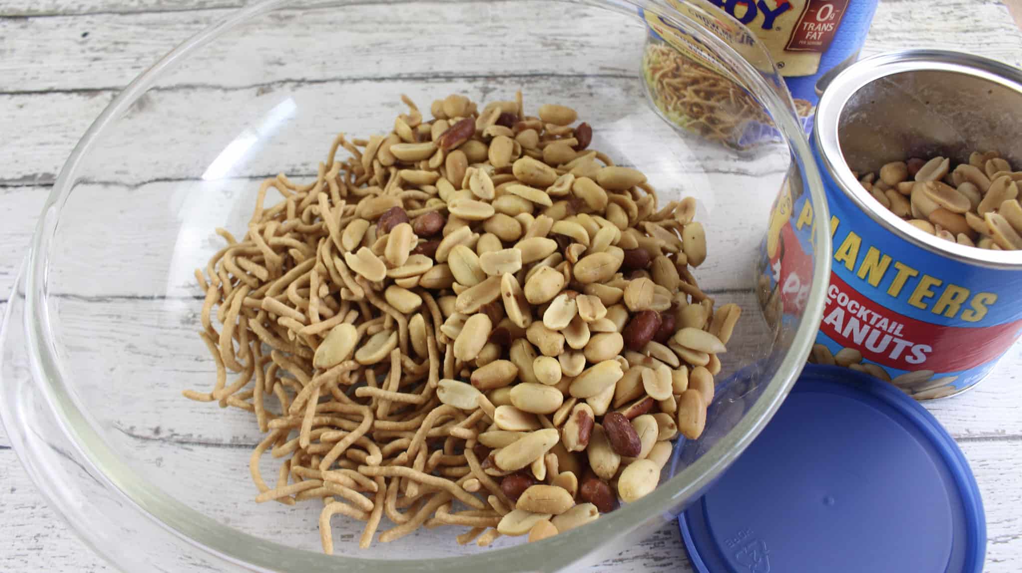 Cocktail peanuts and chow mein noodles in a glass mixing bowl.