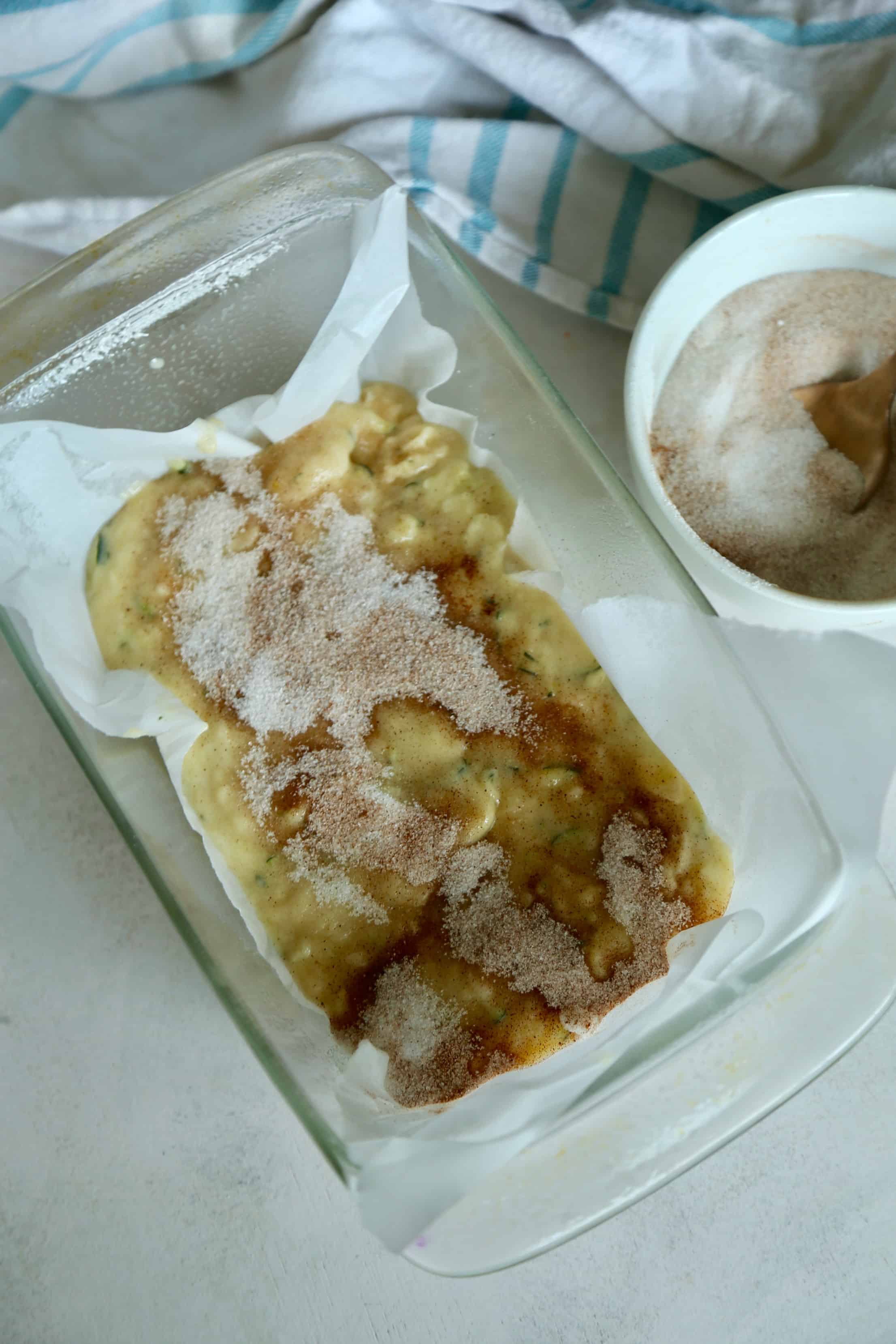 A glass bread pan with snickerdoodle zucchini bread batter inside it.