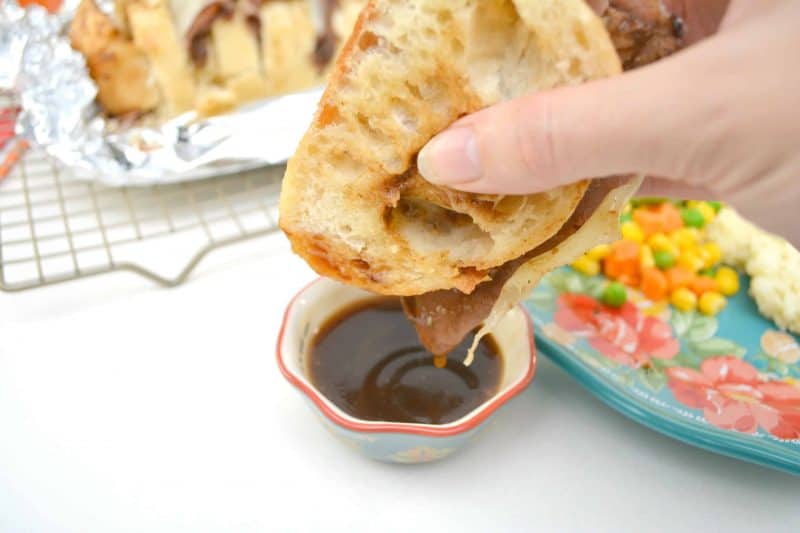 Dipping French dip sandwich into gravy.
