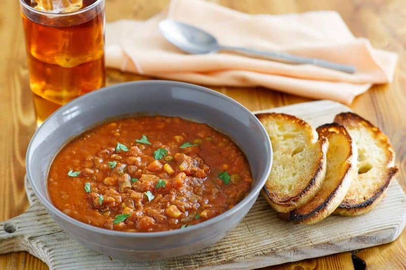 Bowl of lentil stew with crusty bread slices.
