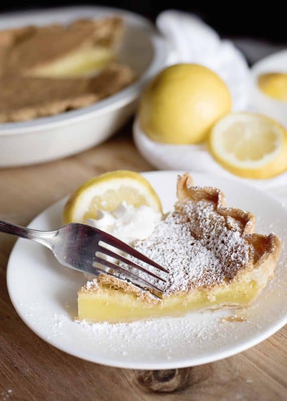 Slice of old-fashioned lemon chess pie, with full pie in background (summer pies).