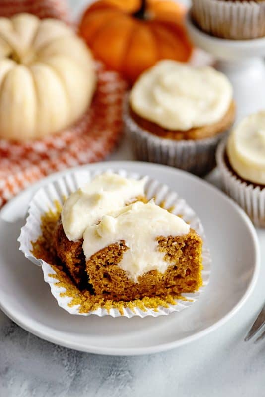 A pumpkin spice cupcake with cream cheese frosting cut open.