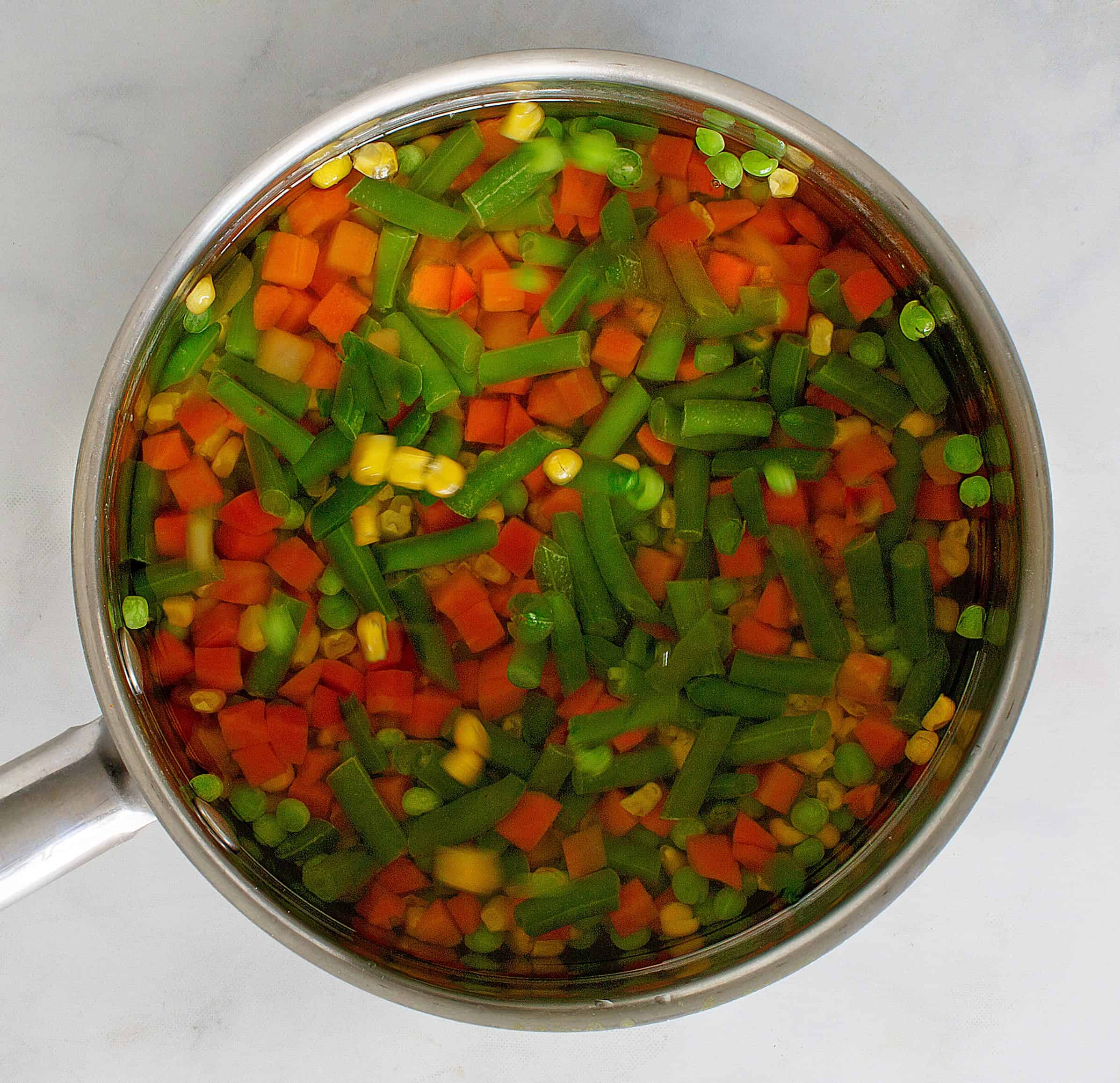 Mixed veggies in saucepan with water.