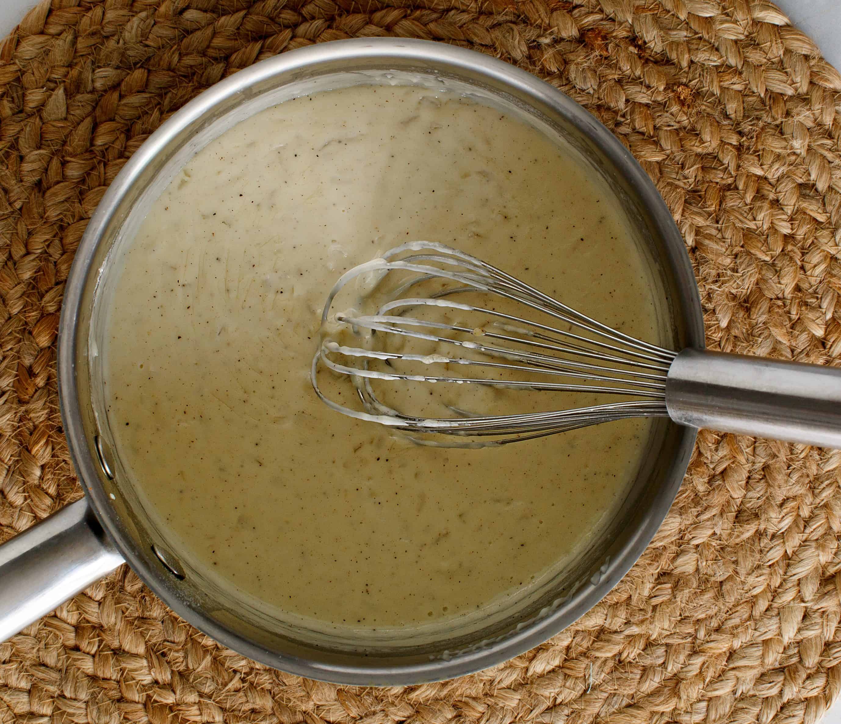 Whisking creamy chicken pot pie filling in a saucepan.