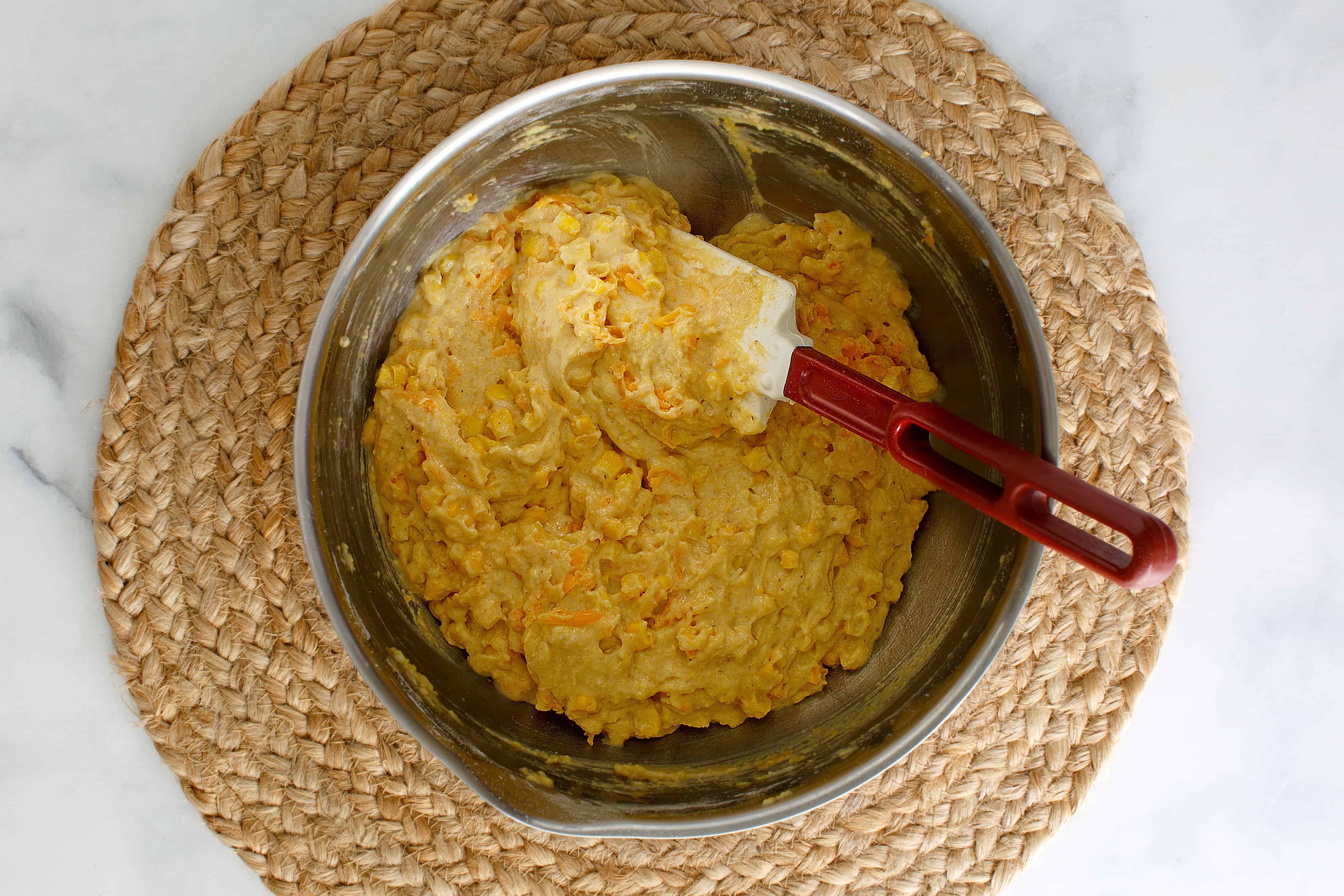 Combining cornbread ingredients in a saucepot with a spatula.