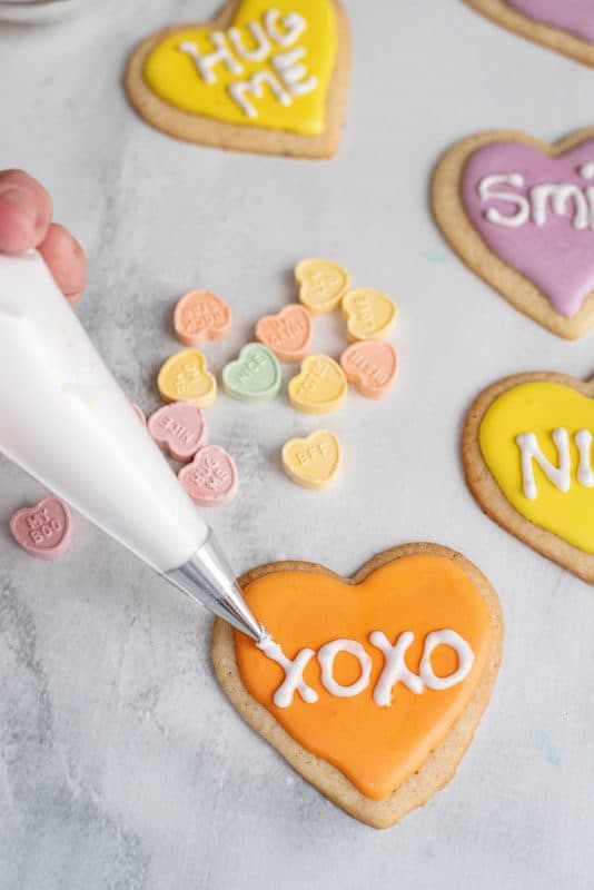 Adding icing to heart shaped Valentine sugar cookies.