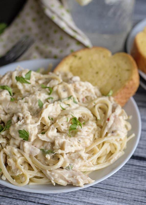 A bowl of crock pot chicken tetrazzini with garlic bread.